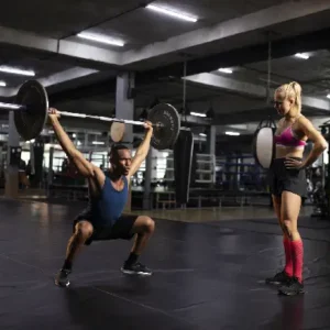 A man and woman are doing squats with barbells.
