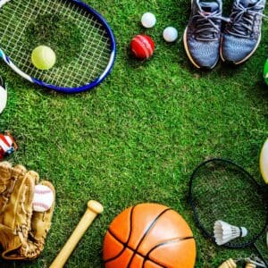 A tennis racket, ball and other sports equipment on the grass.