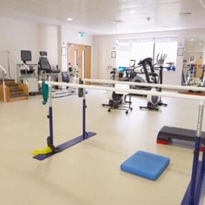 Physiotherapy gym with parallel bars and equipment.